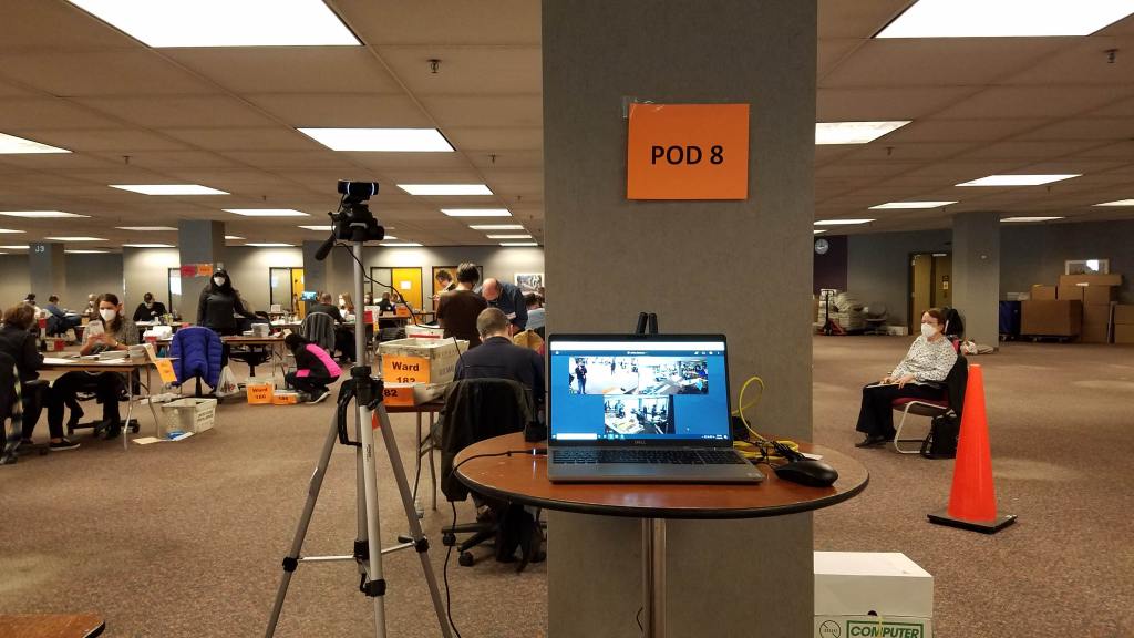 A live-streaming camera setup for the November 3 election and an election observer is seated to the right. 